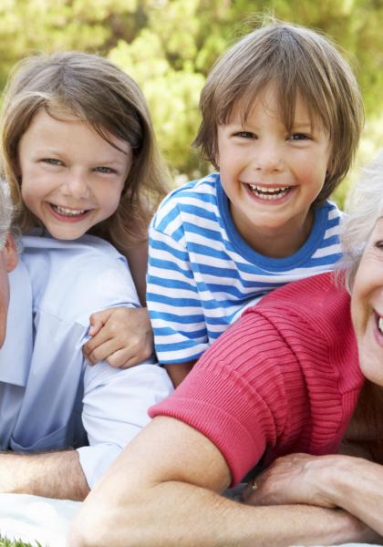 Nonni e nipoti sorridenti sdraiati sull'erba in un giorno di sole.