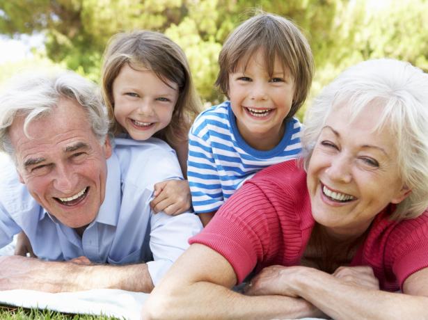 Nonni e nipoti sorridenti sdraiati sull'erba in un giorno di sole.