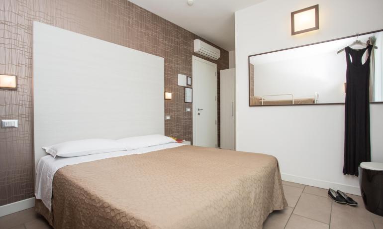 Modern bedroom with double bed and large mirror.