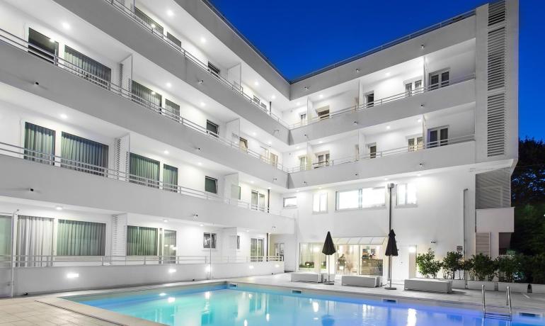 Hôtel moderne avec piscine éclairée la nuit.