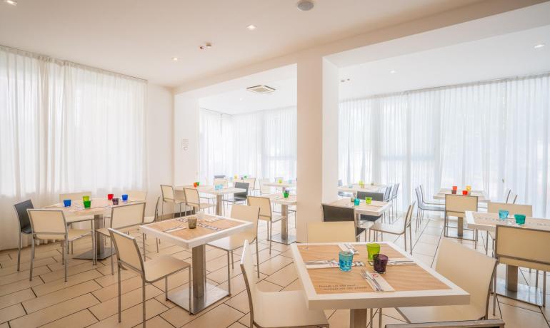 Restaurant moderne avec tables dressées et verres colorés.