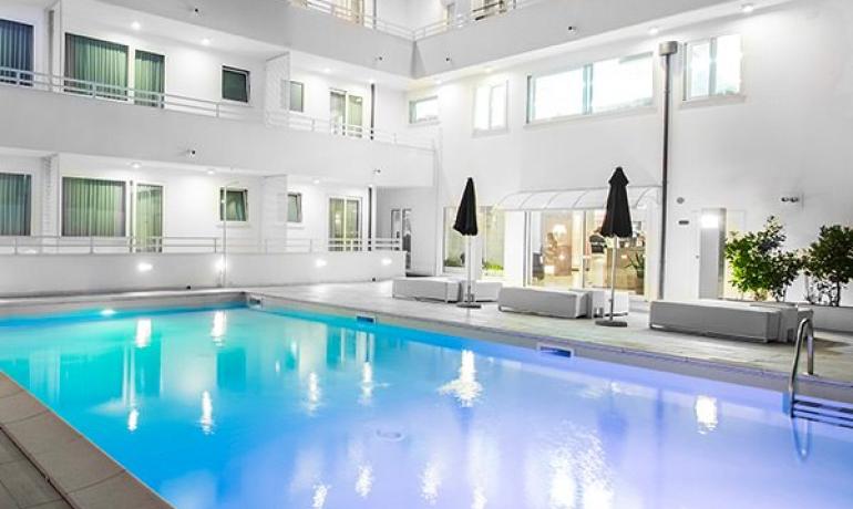 Illuminated pool in a modern white residential complex.