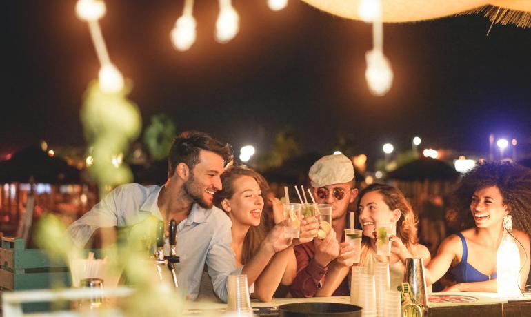 Amici che brindano e si divertono in un bar all'aperto di notte.