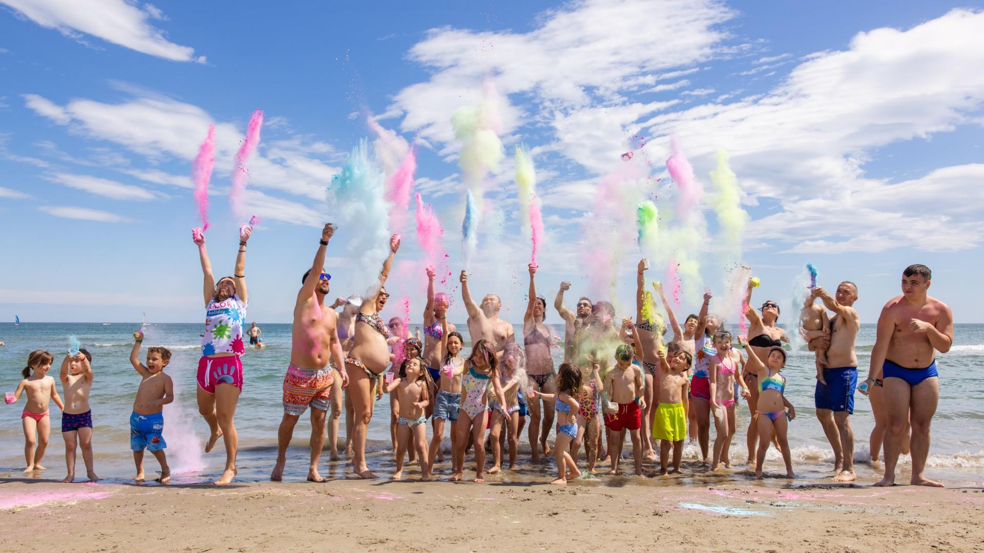 Menschen werfen bunte Pulver am Strand an einem sonnigen Tag.