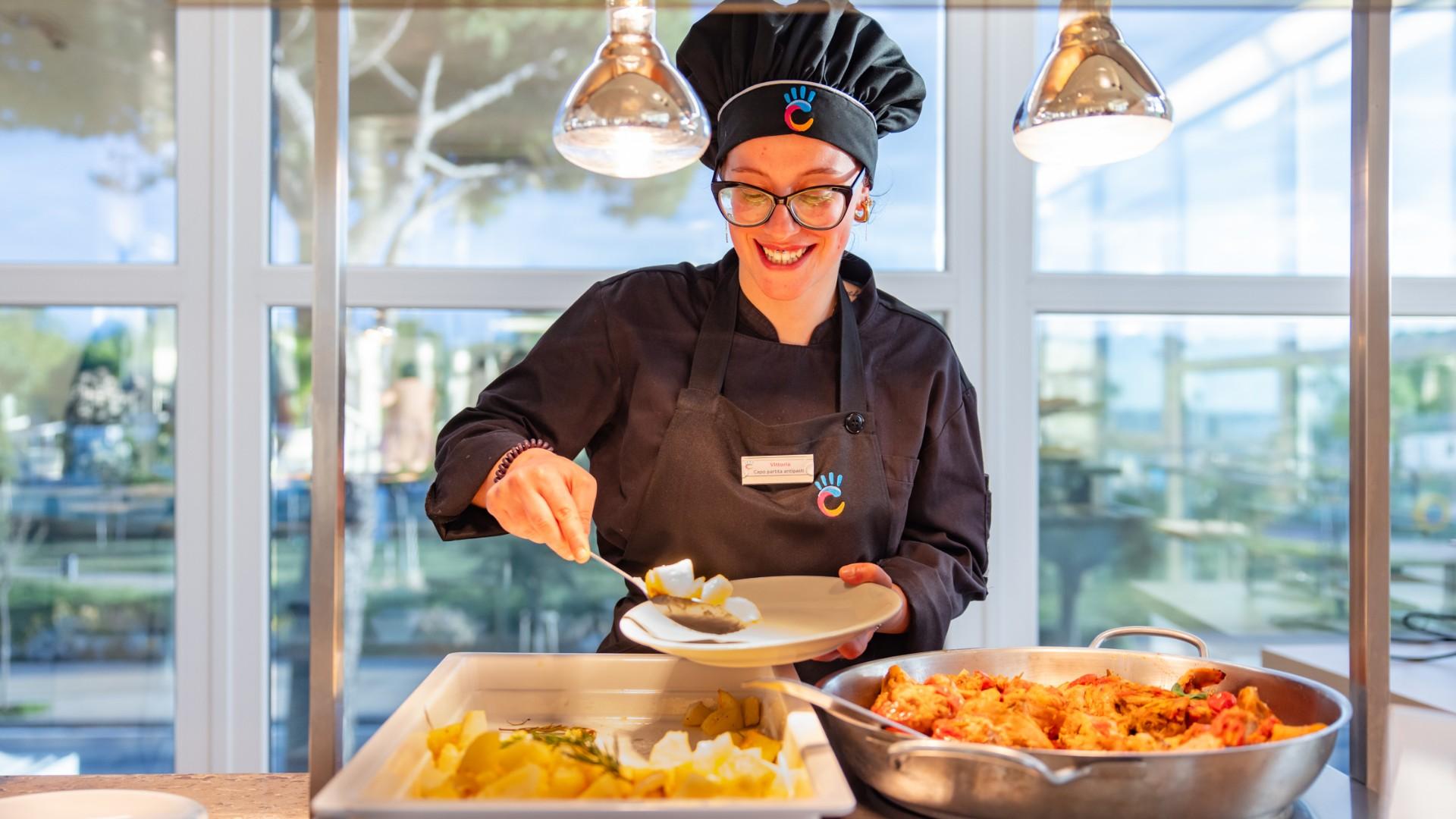 Chef souriante sert de la nourriture dans un restaurant lumineux.