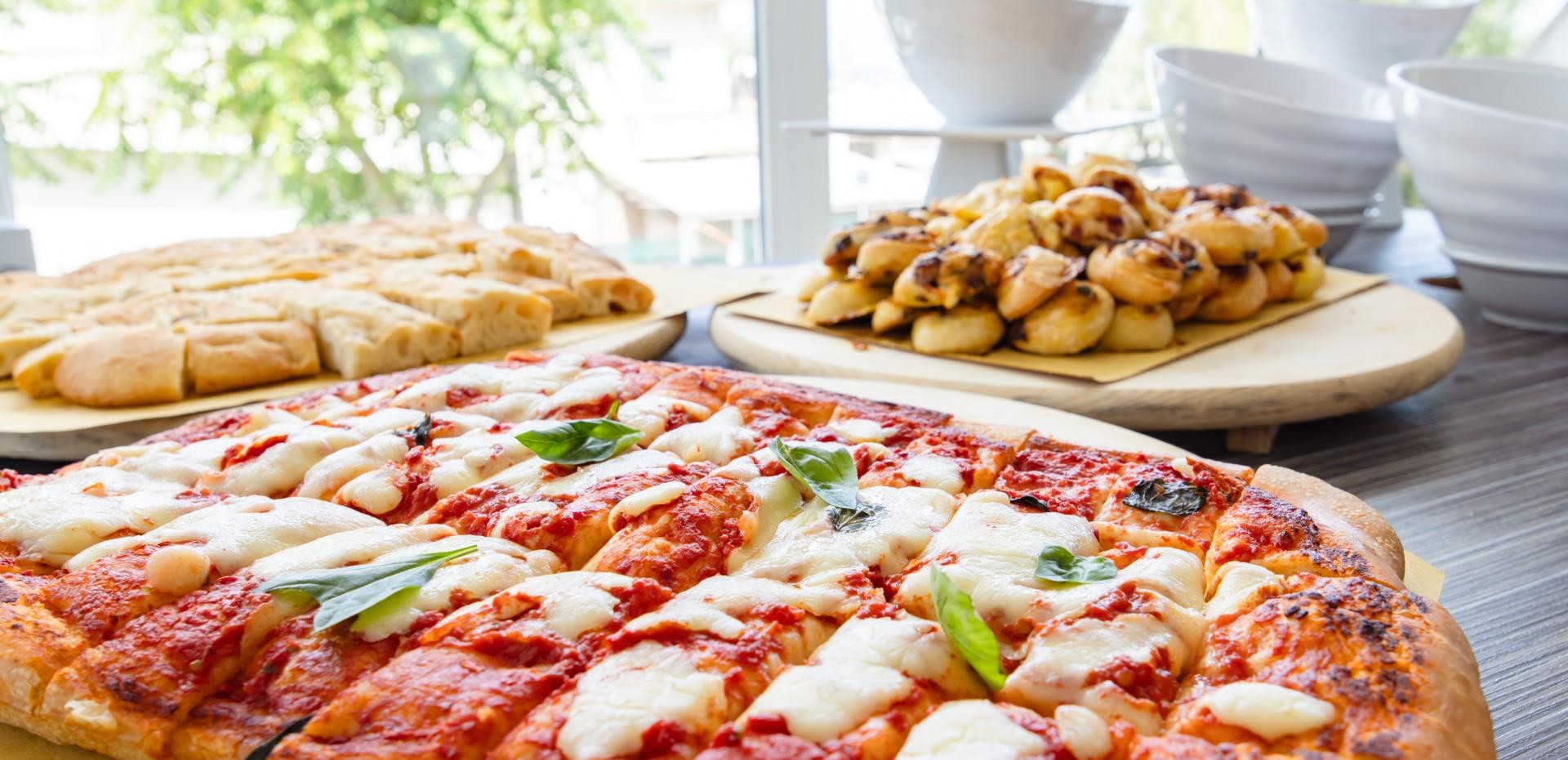 Pizza margherita avec basilic et pain en arrière-plan.