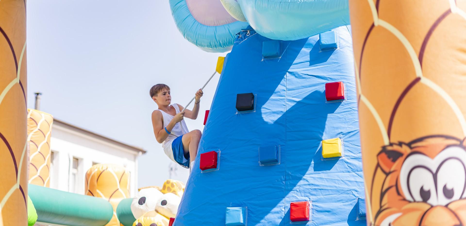 Enfant escalade un mur gonflable coloré dans un parc de jeux.
