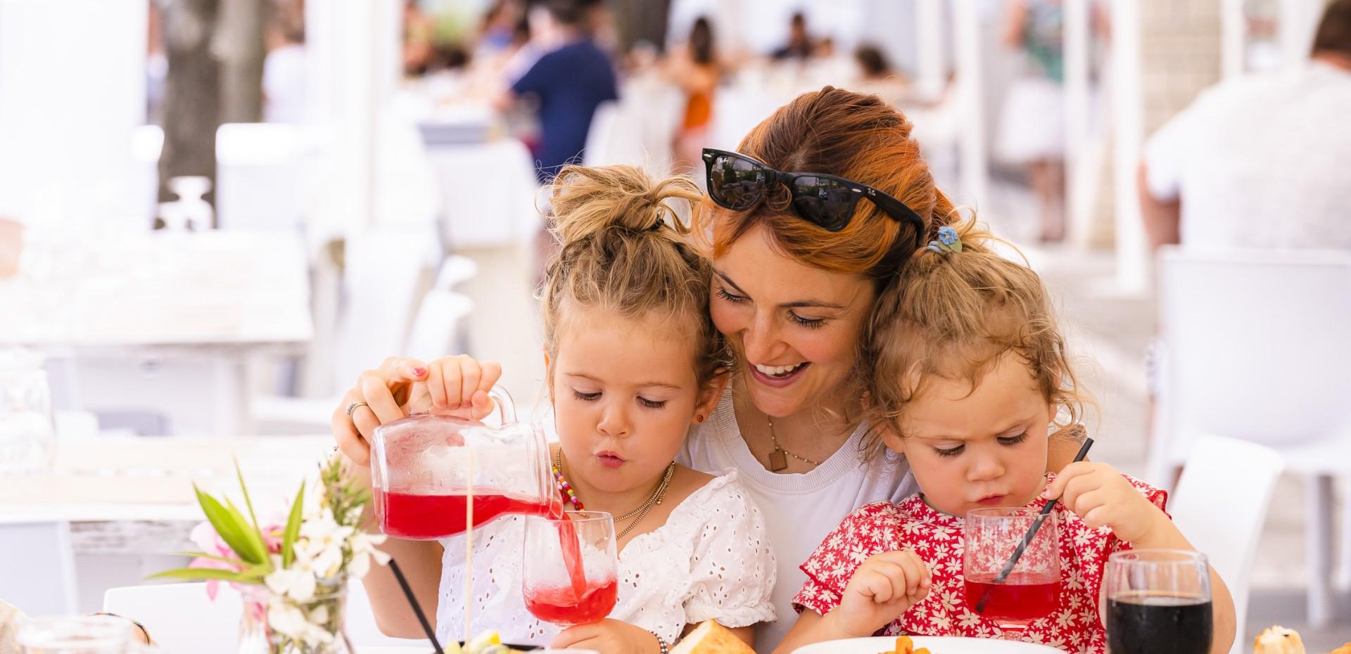 Mère et filles sourient en buvant ensemble au restaurant.