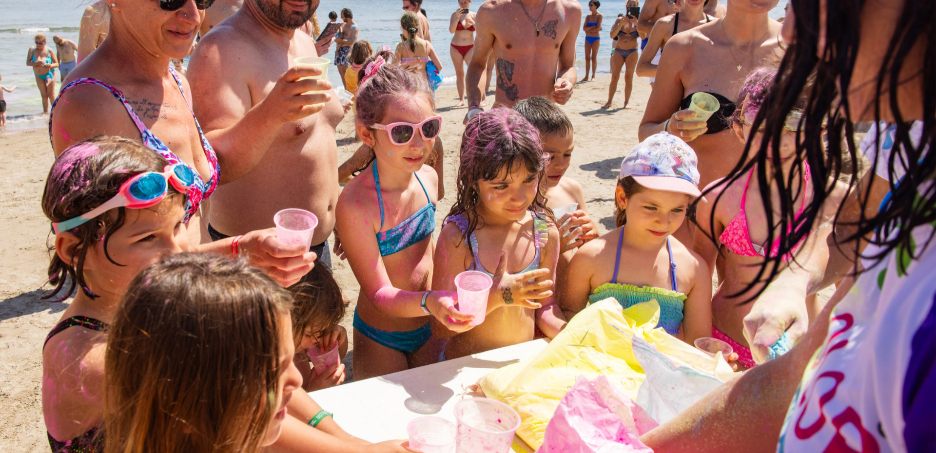 Beach party, colorful children smiling and playing with adults under the summer sun.