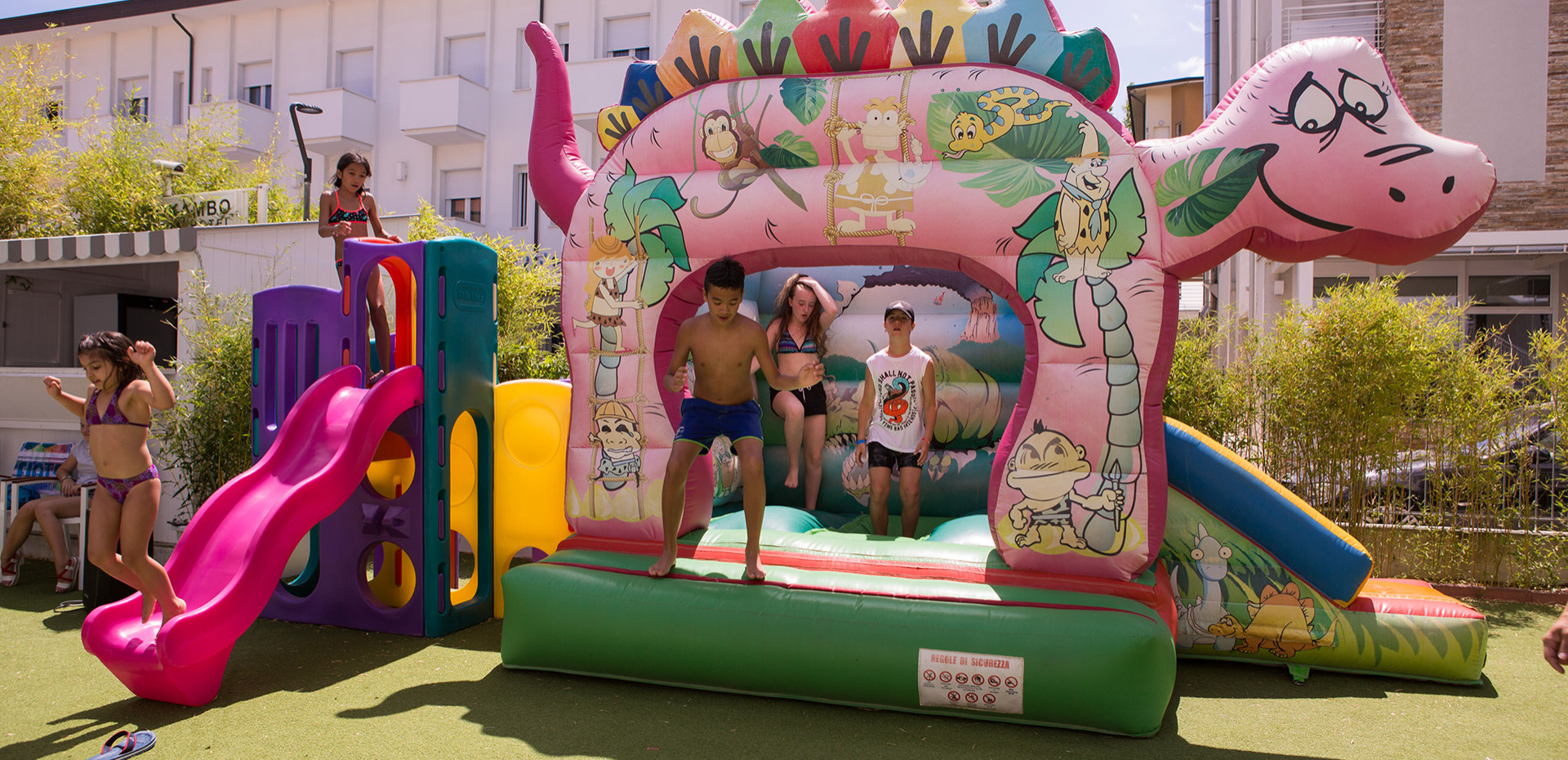 Children joyfully play on colorful inflatables under the sunny sky.