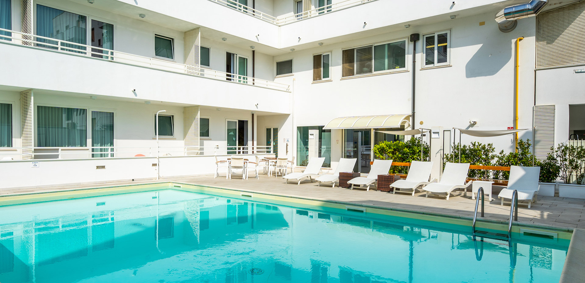 Piscina coperta con colonne verdi, decorazioni marine e area relax.