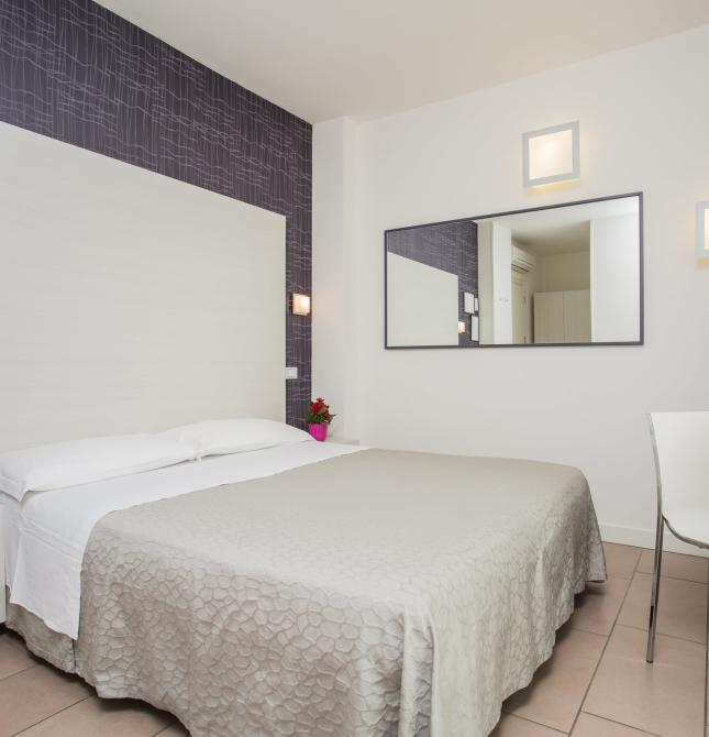 Bright, modern room with a double bed and colorful flowers.