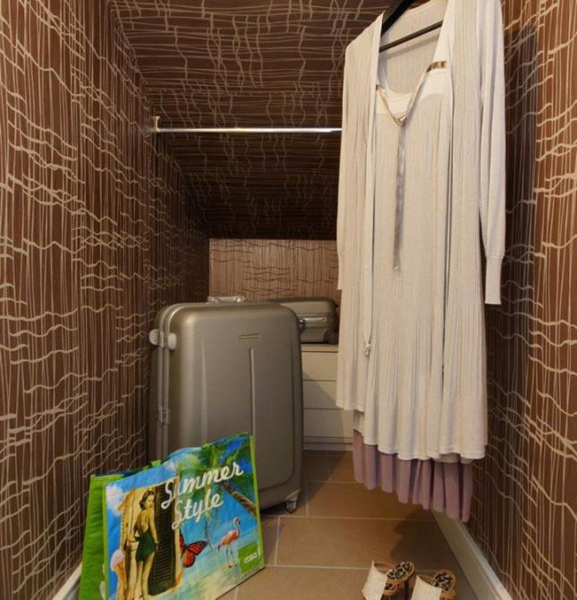 Cozy nook with summer clothes, suitcase, and stylish sandals.