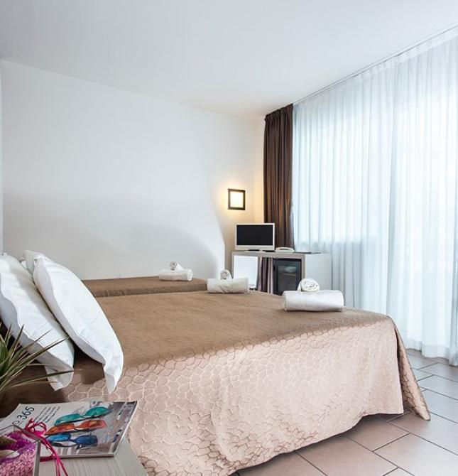 Bright room with twin beds, white curtains, and modern decor.