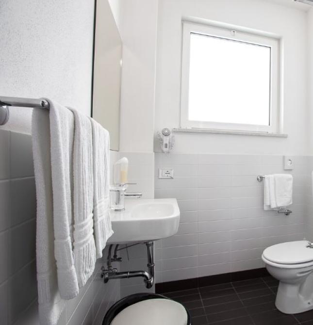 Modern, bright, clean bathroom with glass shower and white towels.