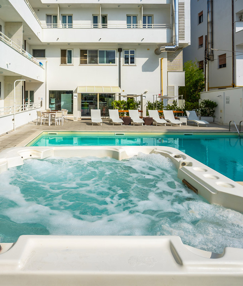 Piscina per bambini con giochi d'acqua e gonfiabile colorato in cortile soleggiato.